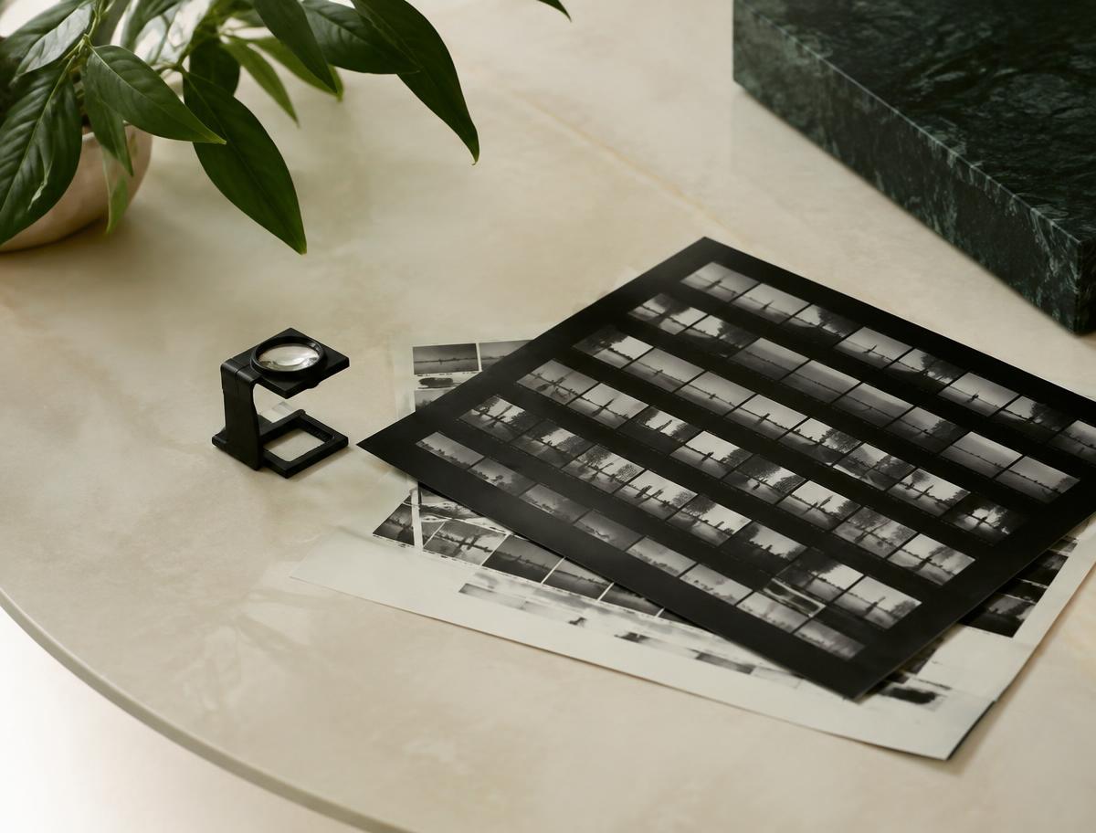 Photographic contact sheets and a loupe on an ivory table